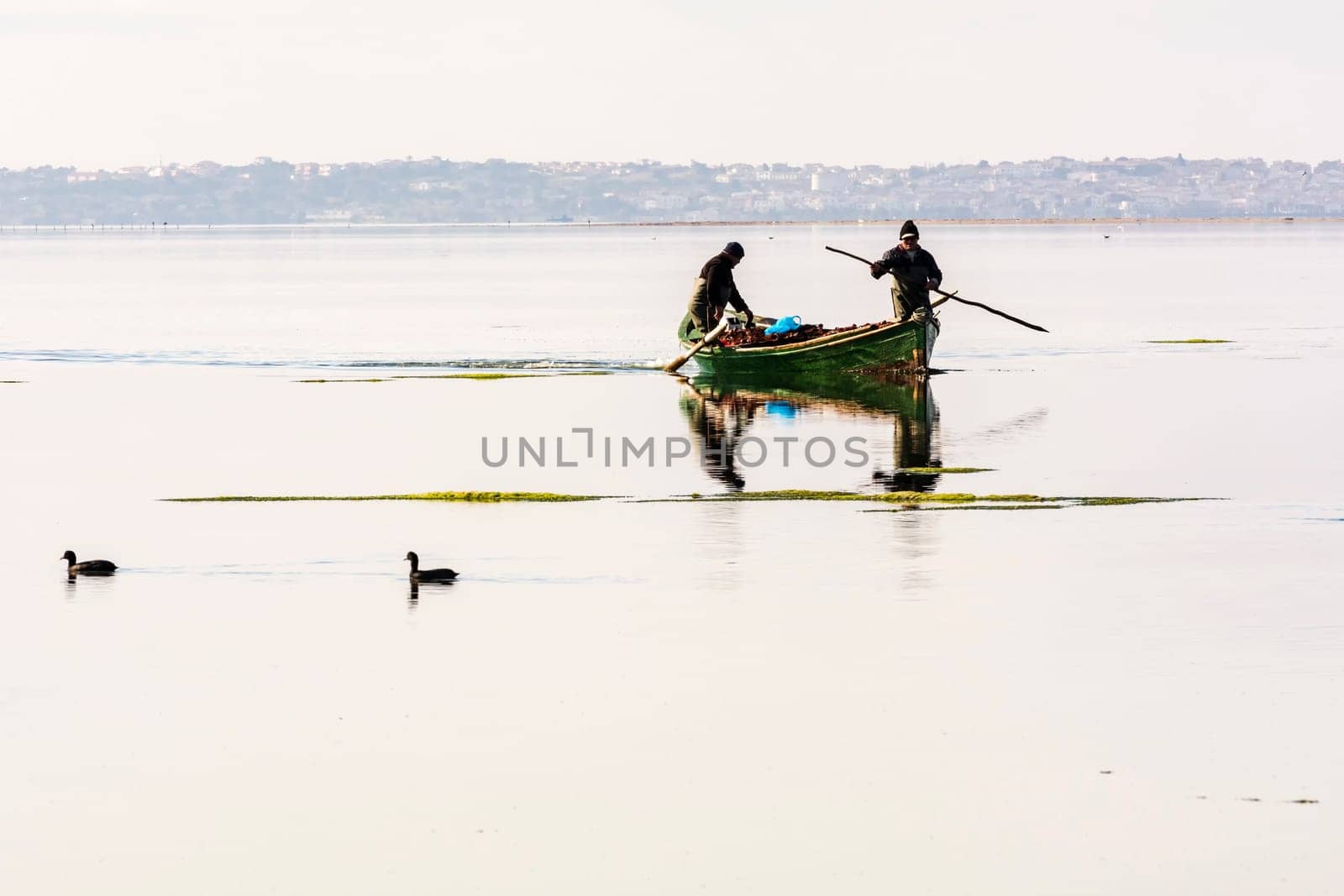 Bruncuteula, Sant'Antioco, Italy - January 28, 2016: Fishermen with their ancient boats, fall at dawn, landscape of the lagoon of Sant'Antioco in south west Sardinia.