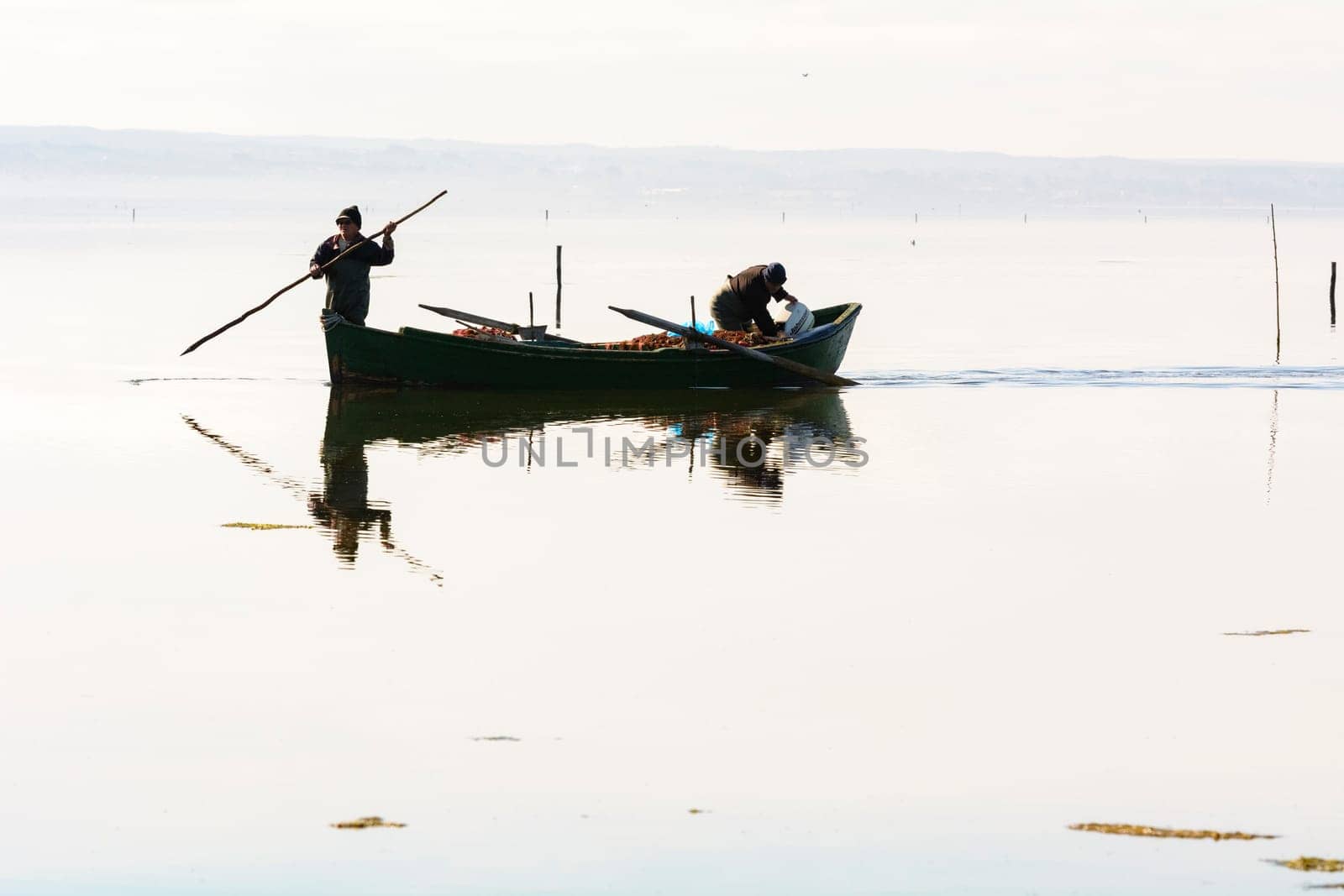 Bruncuteula, Sant'Antioco, Italy - January 28, 2016: Fishermen with their ancient boats, fall at dawn, landscape of the lagoon of Sant'Antioco in south west Sardinia.
