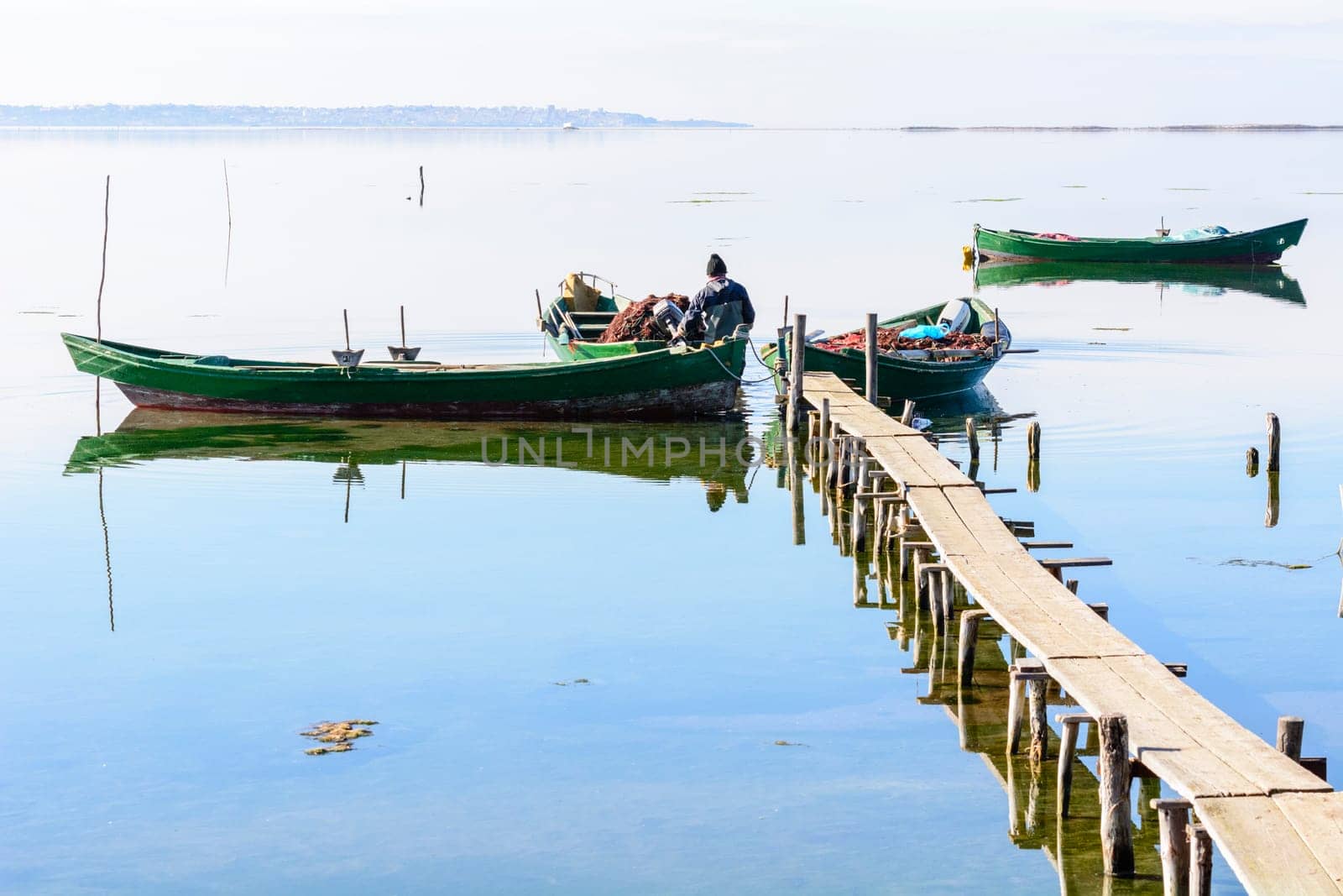 Bruncuteula, Sant'Antioco, Italy - January 28, 2016: Fishermen with their ancient boats, fall at dawn, landscape of the lagoon of Sant'Antioco in south west Sardinia.