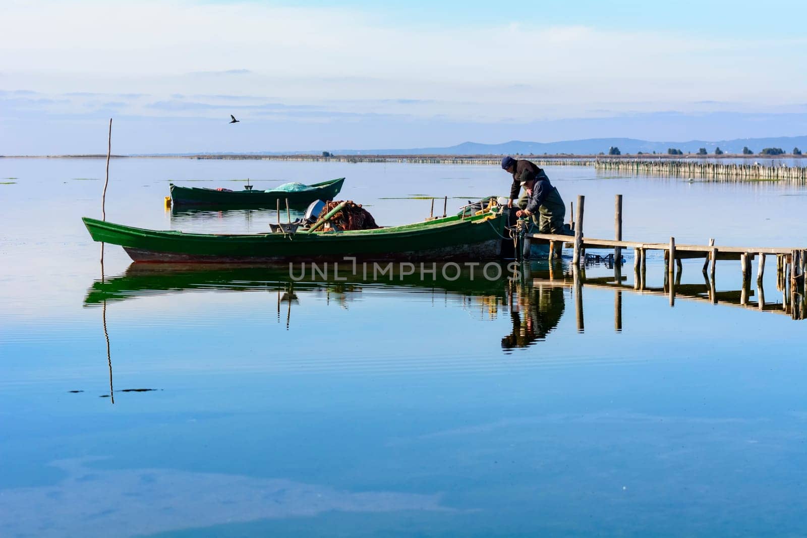 Bruncuteula, Sant'Antioco, Italy - January 28, 2016: Fishermen with their ancient boats, fall at dawn, landscape of the lagoon of Sant'Antioco in south west Sardinia.