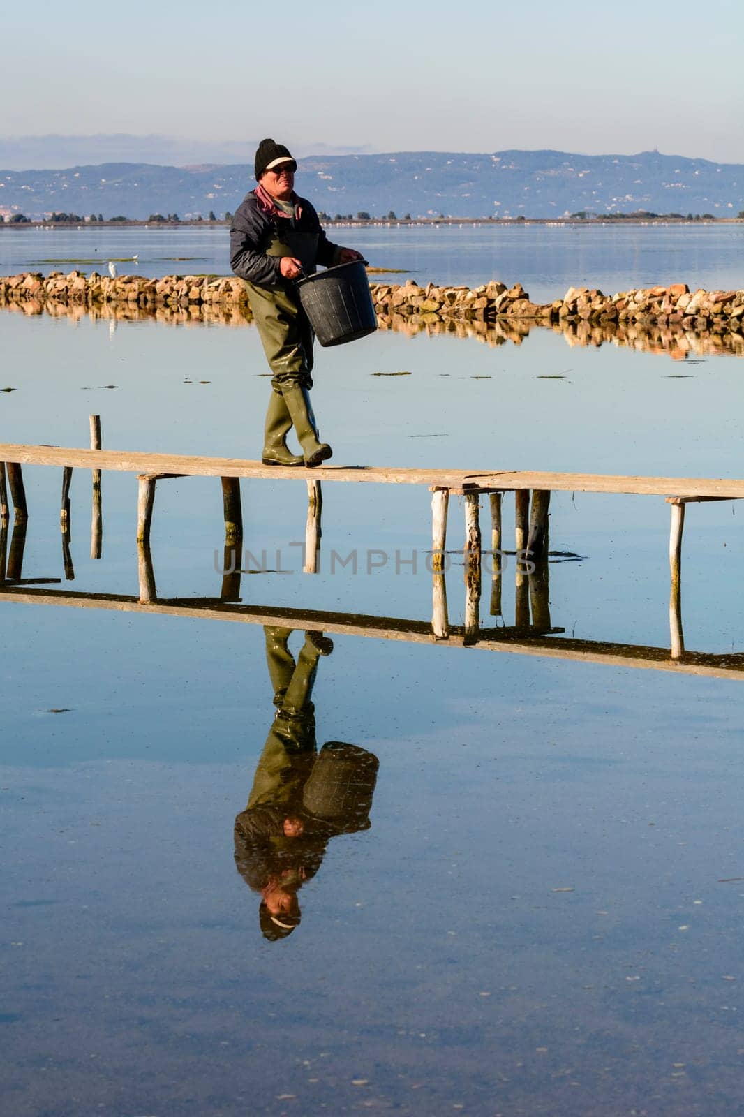 Bruncuteula, Sant'Antioco, Italy - January 28, 2016: Fishermen with their ancient boats, fall at dawn, landscape of the lagoon of Sant'Antioco in south west Sardinia.