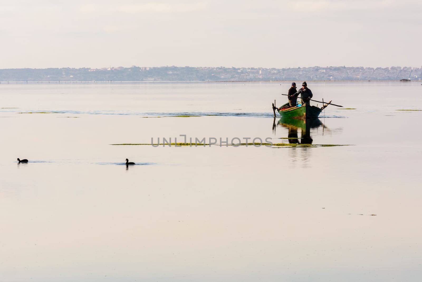 Bruncuteula, Sant'Antioco, Italy - January 28, 2016: Fishermen with their ancient boats, fall at dawn, landscape of the lagoon of Sant'Antioco in south west Sardinia.
