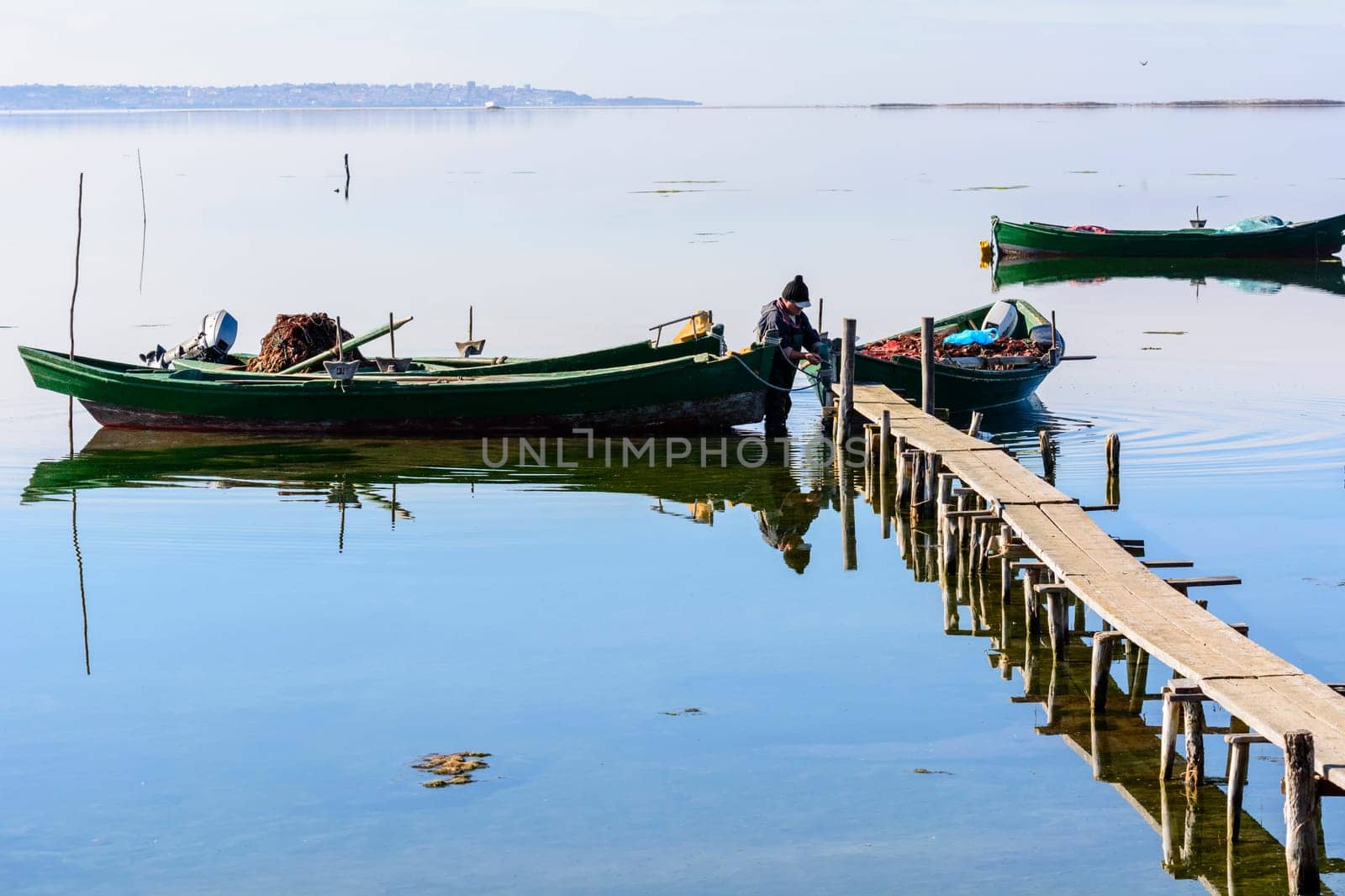 Bruncuteula, Sant'Antioco, Italy - January 28, 2016: Fishermen with their ancient boats, fall at dawn, landscape of the lagoon of Sant'Antioco in south west Sardinia.