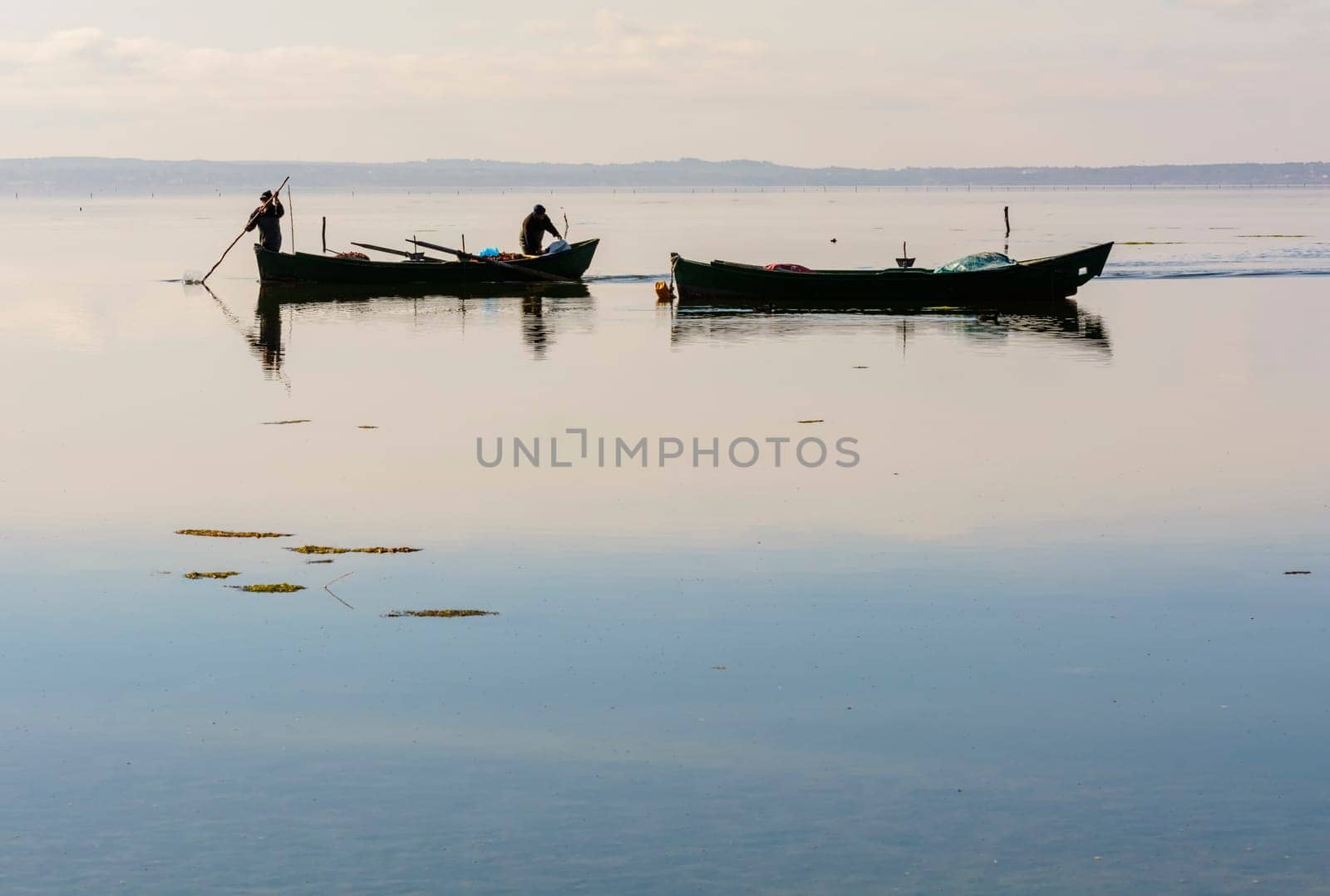 Bruncuteula, Sant'Antioco, Italy - January 28, 2016: Fishermen with their ancient boats, fall at dawn, landscape of the lagoon of Sant'Antioco in south west Sardinia.
