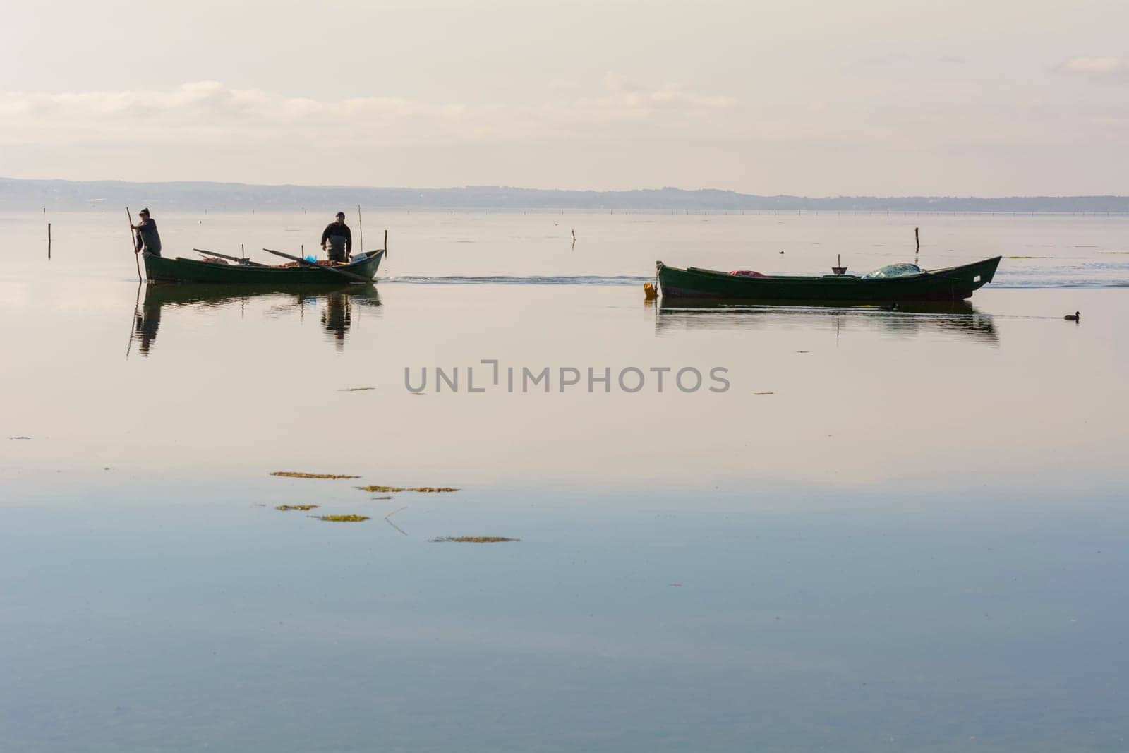 Bruncuteula, Sant'Antioco, Italy - January 28, 2016: Fishermen with their ancient boats, fall at dawn, landscape of the lagoon of Sant'Antioco in south west Sardinia.