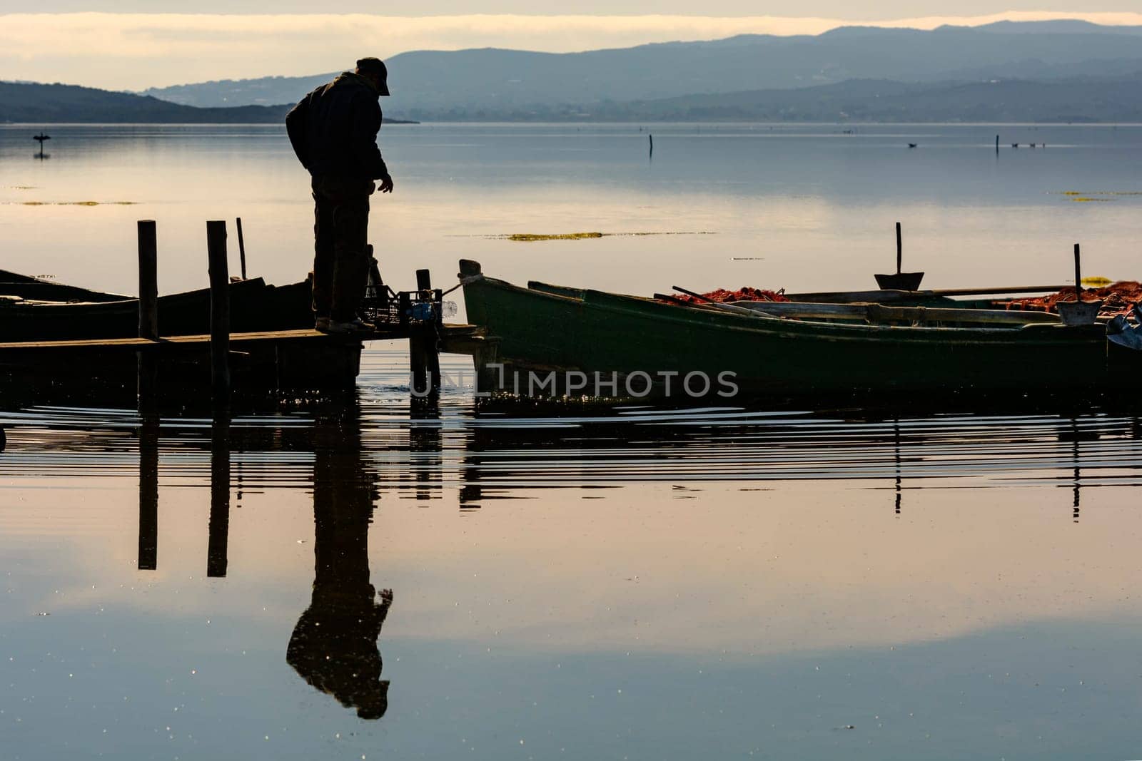Bruncuteula, Sant'Antioco, Italy - January 28, 2016: Fishermen with their ancient boats, fall at dawn, landscape of the lagoon of Sant'Antioco in south west Sardinia.