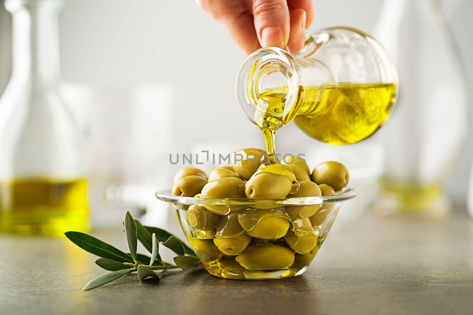 Organic olive oil. Bottle of Extra virgin oil pouring in to glass bowl with olives