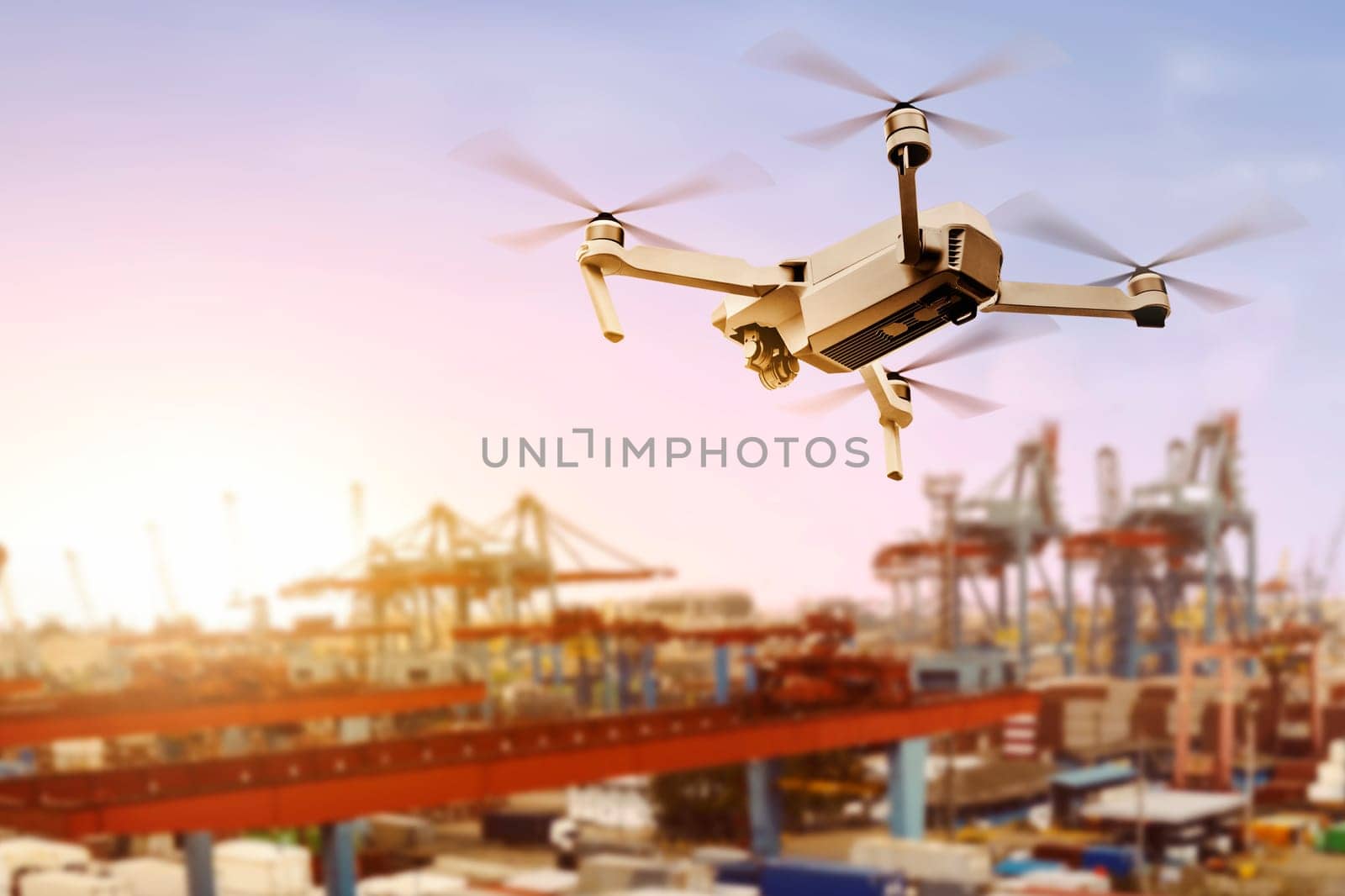 White drone with camera flying above the dock with sunset view background