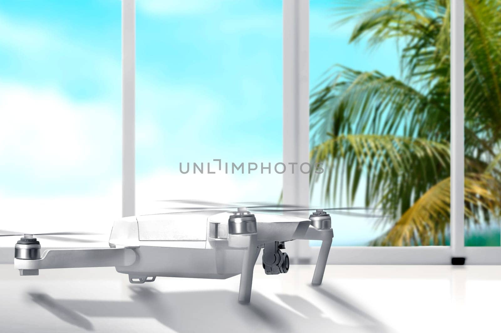 White drone with camera on white table with window glass and palm tree with blue sky background