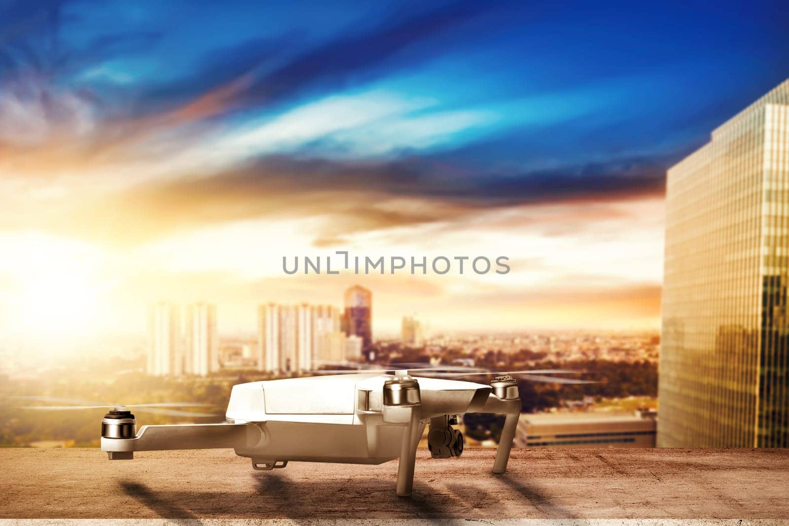 White drone with camera on the rooftop ready to flying to the air with cityscapes at sunset background