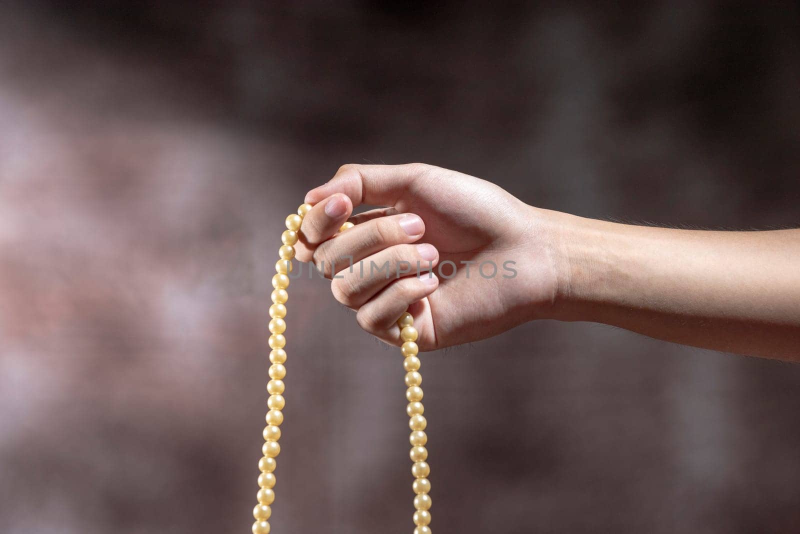 Muslim hands praying with prayer beads over blurry background