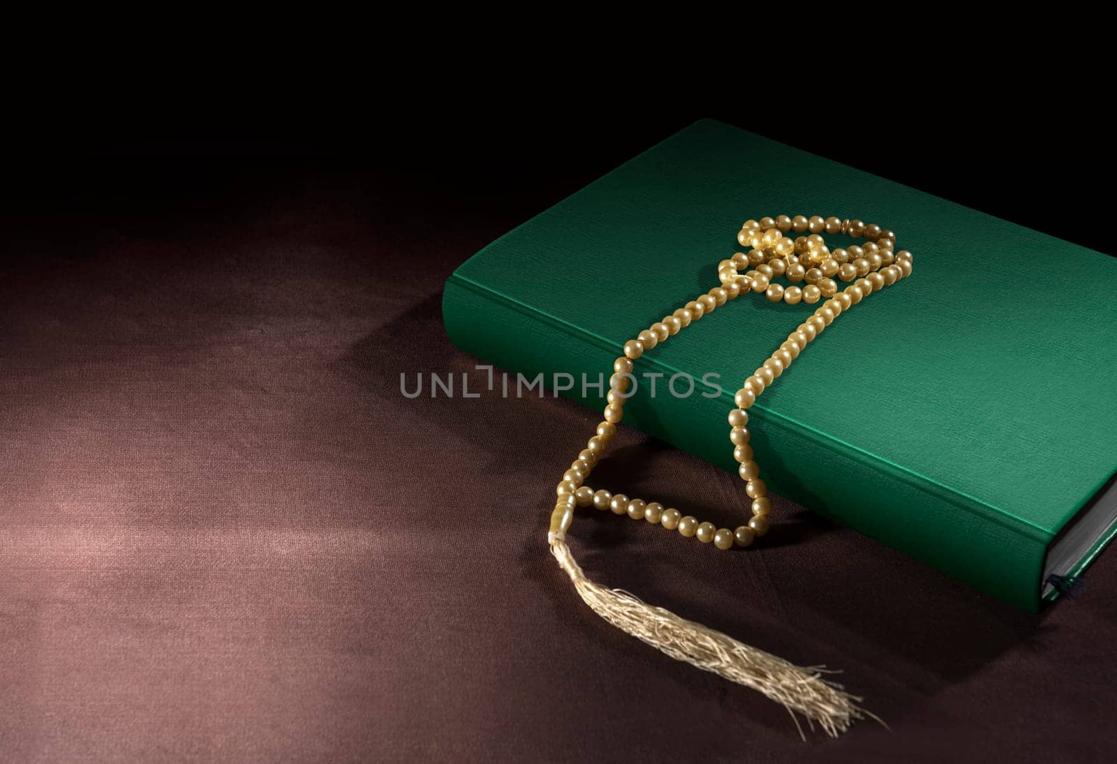 Quran and prayer beads on the table over black background