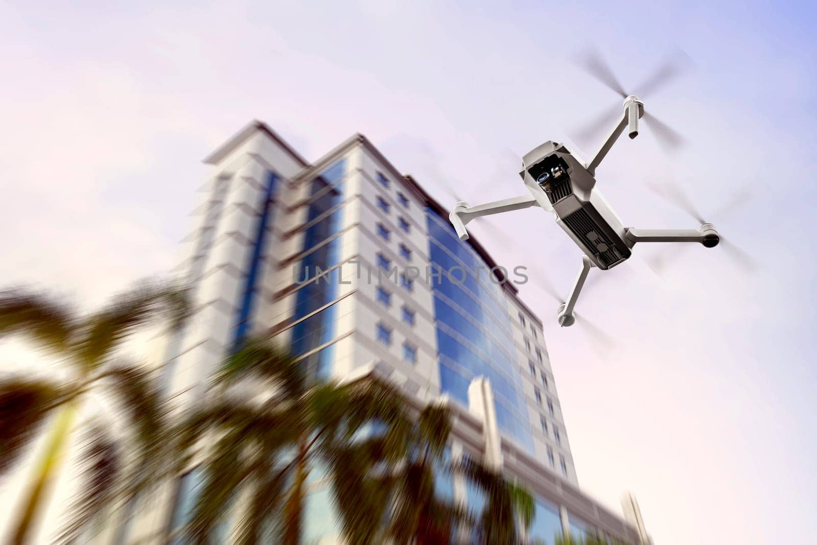 White drone with camera flying to the top of modern building with afternoon background