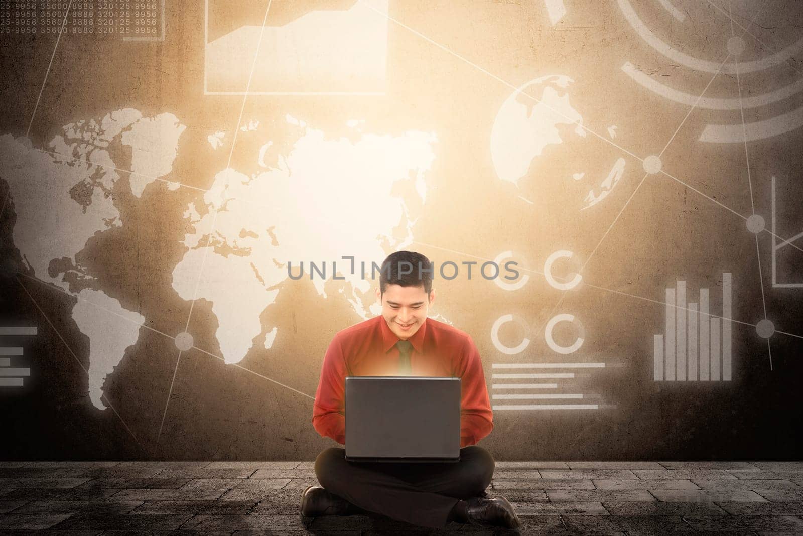 Smiling asian businessman sitting and using laptop with virtual screen which display the interface of financial chart and world maps. Digital technology concept