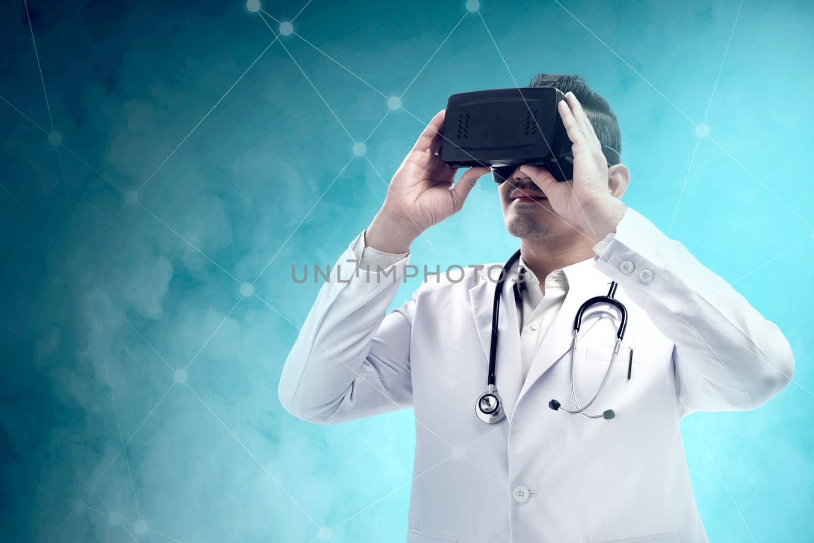 Asian male doctor in white coat and stethoscope using virtual reality device. Digital technology concept