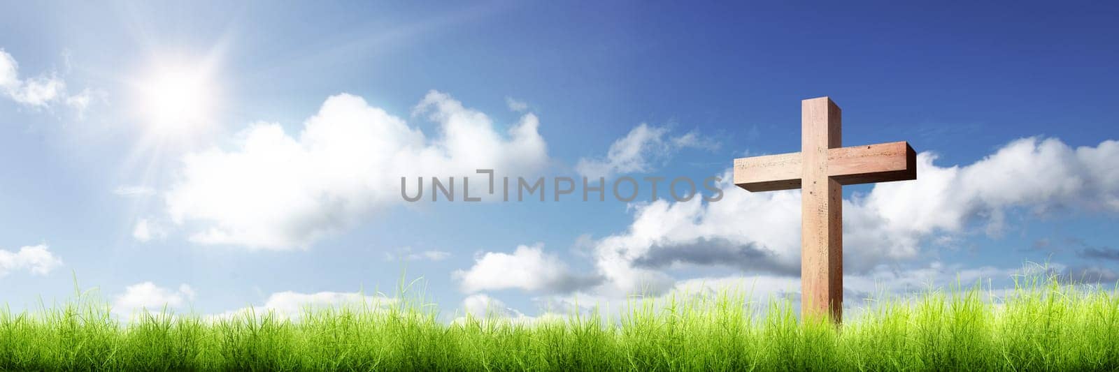 Christian cross on the green grass with sunlight over blue sky background