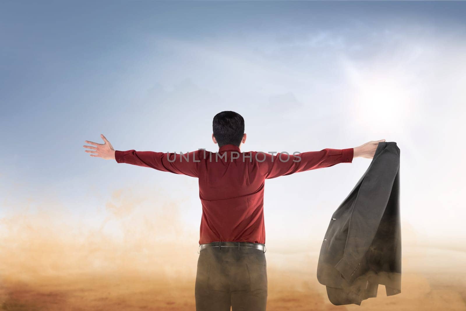 Rear view of asian businessman raised hands with open palm praying to god over blue sky background