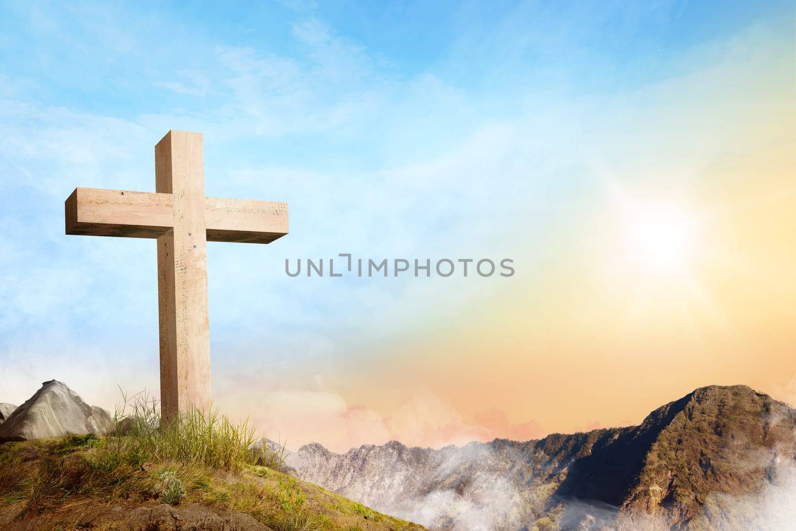 Christian cross on the of mountain with clouds fog over sunrise background