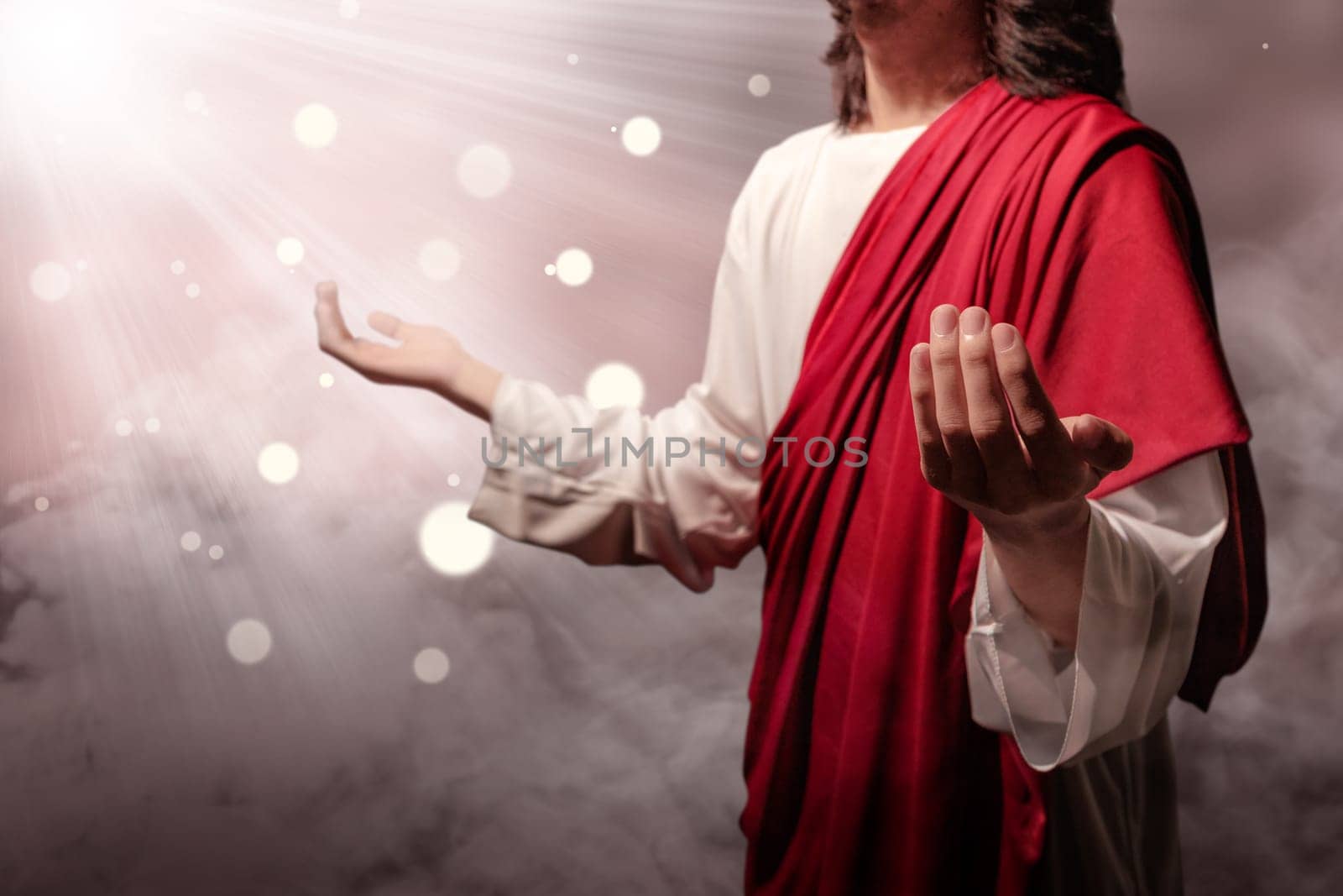 Jesus christ raised hands and praying to god with ray over blurry background