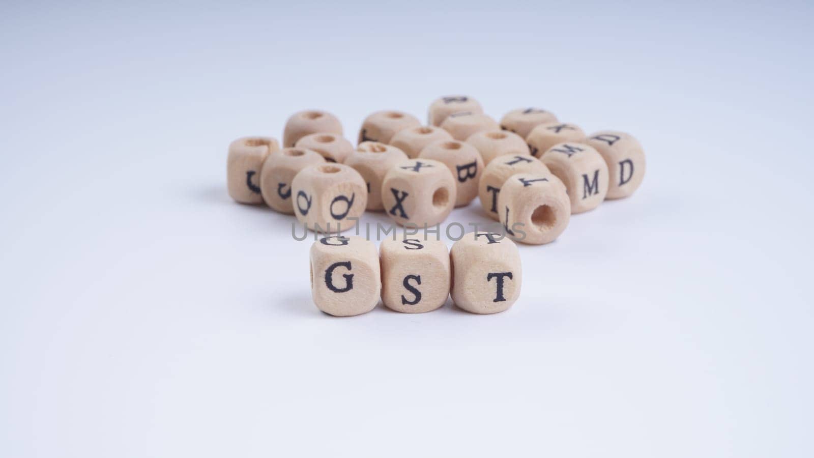 GST inscription on wooden alphabet over white background with selective focus