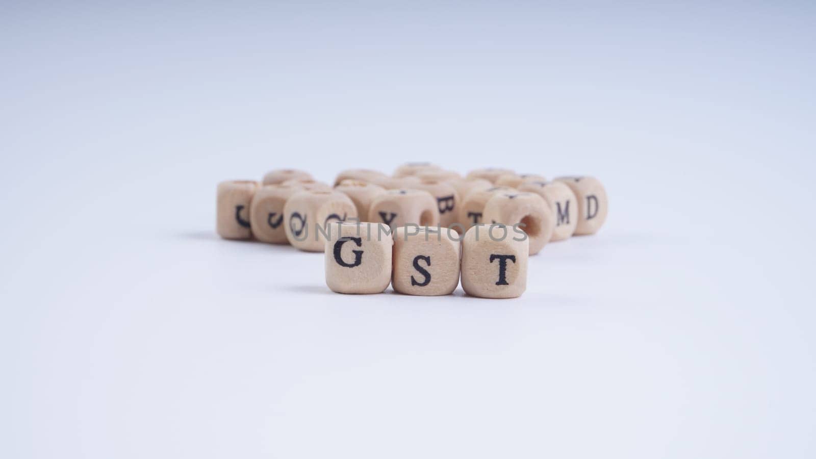 GST inscription on wooden alphabet over white background with selective focus