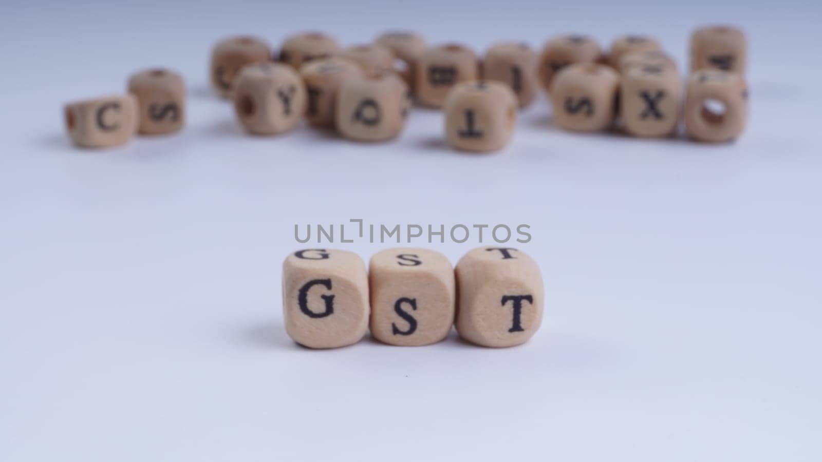 GST inscription on wooden alphabet over white background with selective focus