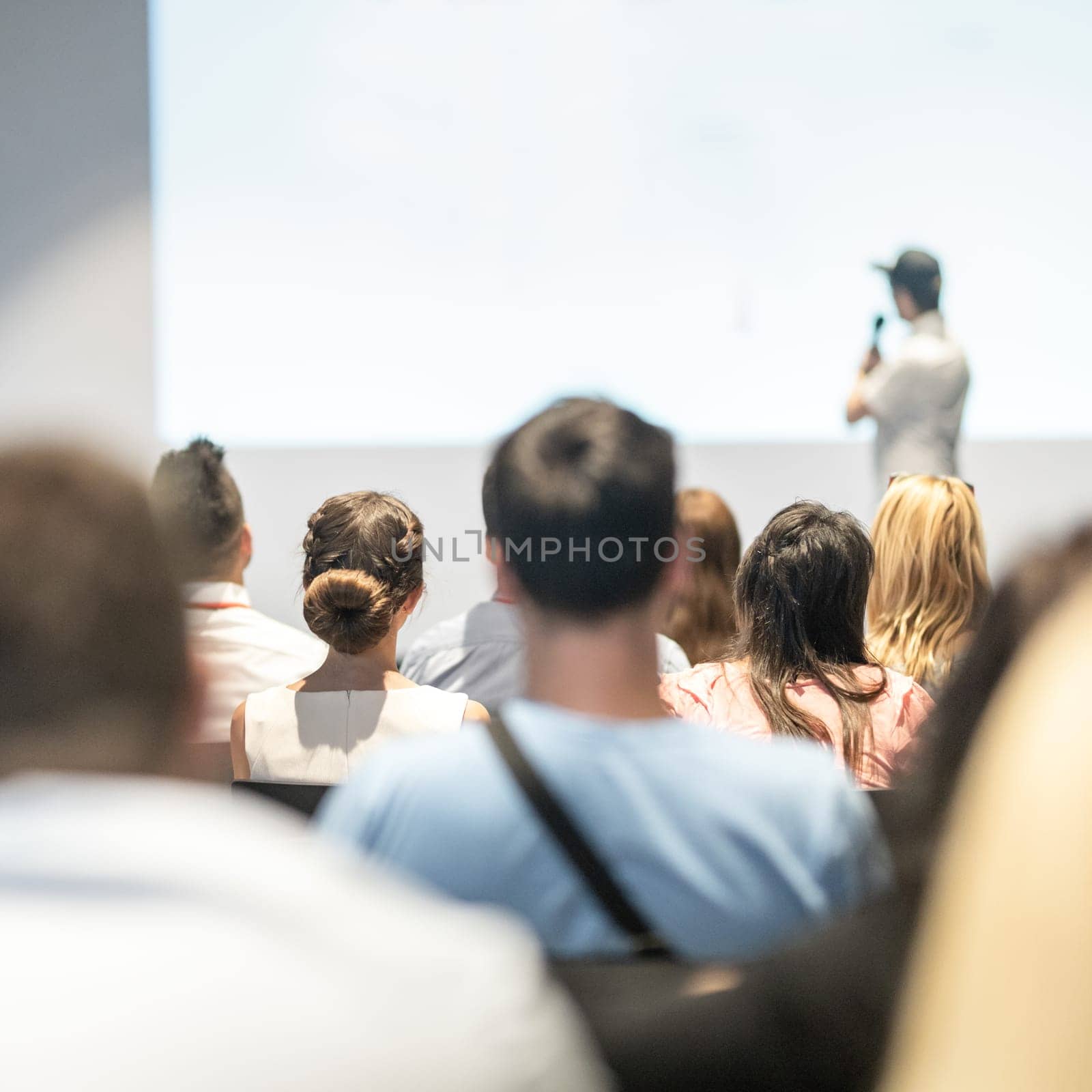 Speaker giving a talk in conference hall at business event. Audience at the conference hall. Business and Entrepreneurship concept. Focus on unrecognizable people in audience.