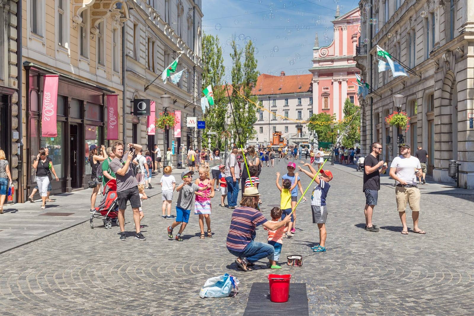 Ljubljana, Slovenia - Aug 9, 2016: Urban street artist performing a soap bubble show for children in medieval city center of Slovenian capital Ljubljana in summer on 9th of August, 2016.