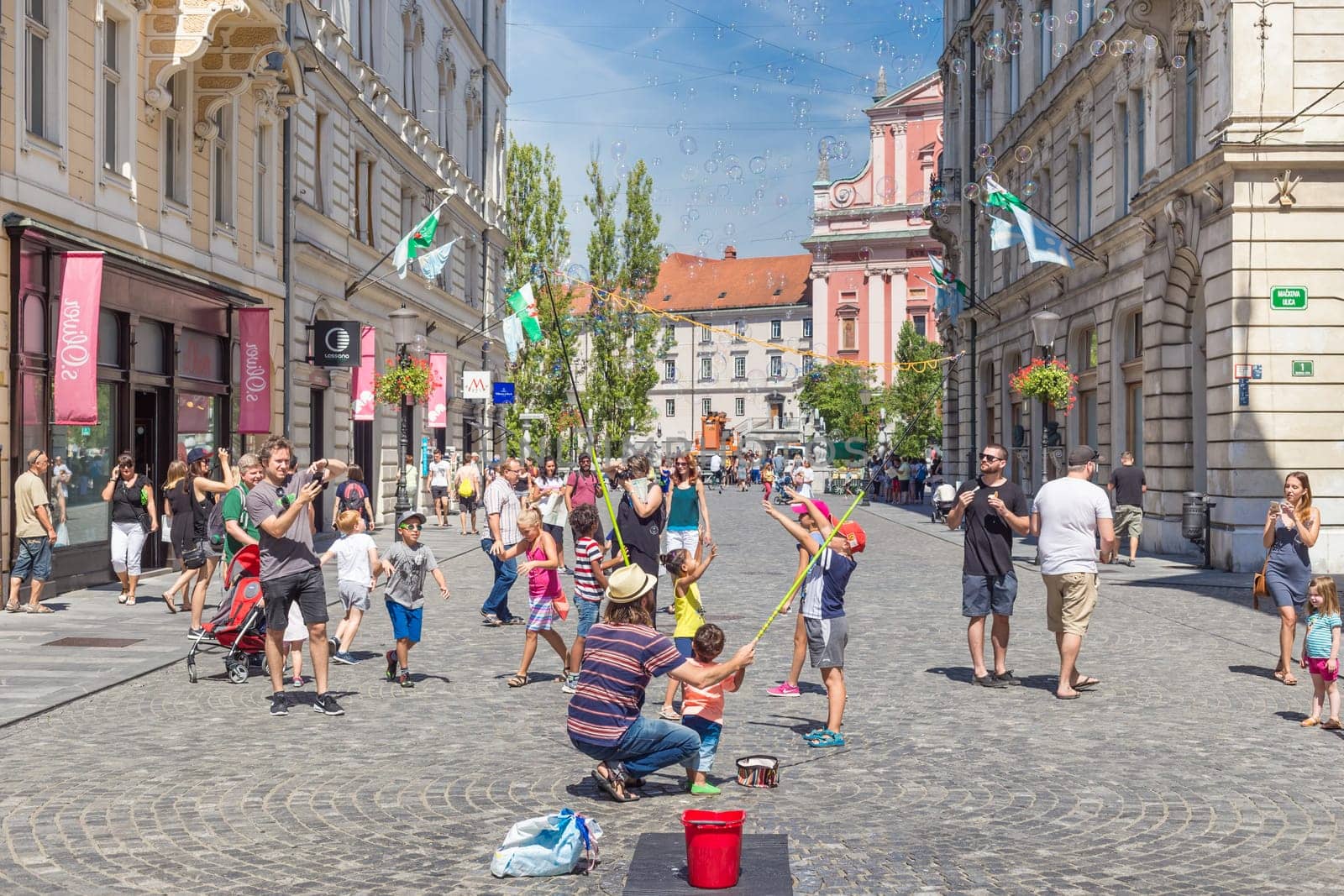Ljubljana, Slovenia - Aug 9, 2016: Urban street artist performing a soap bubble show for children in medieval city center of Slovenian capital Ljubljana in summer on 9th of August, 2016.