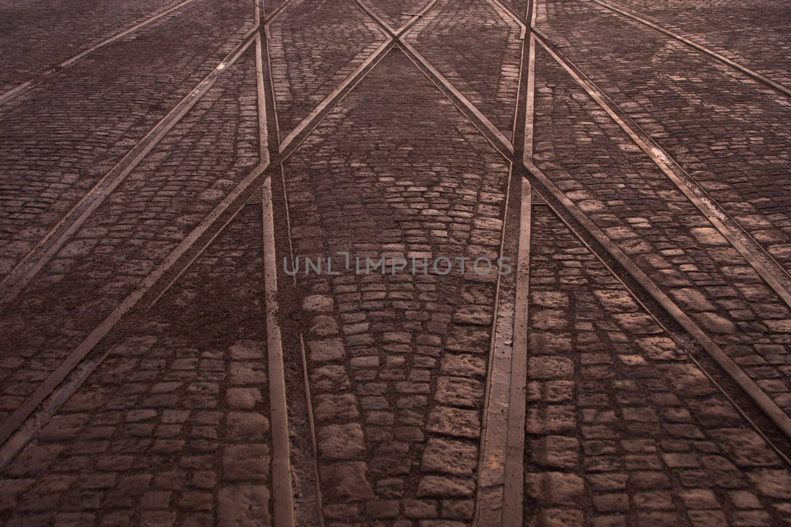 Crossing of tram rails on stone pavement background