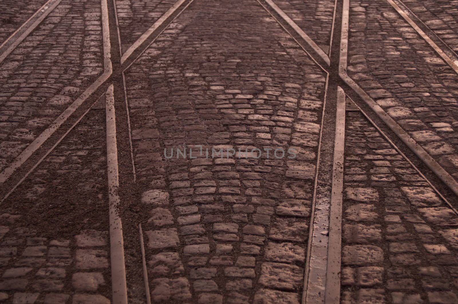 Crossing of tram rails on stone pavement background
