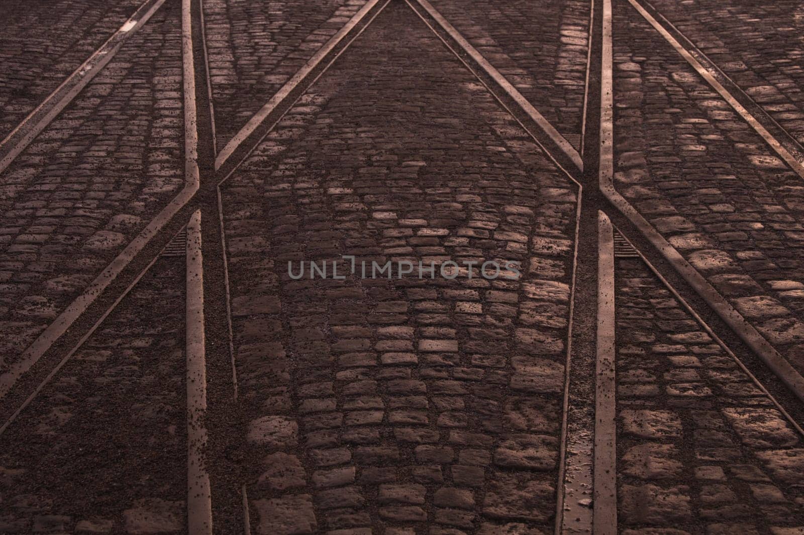 Crossing of tram rails on stone pavement background