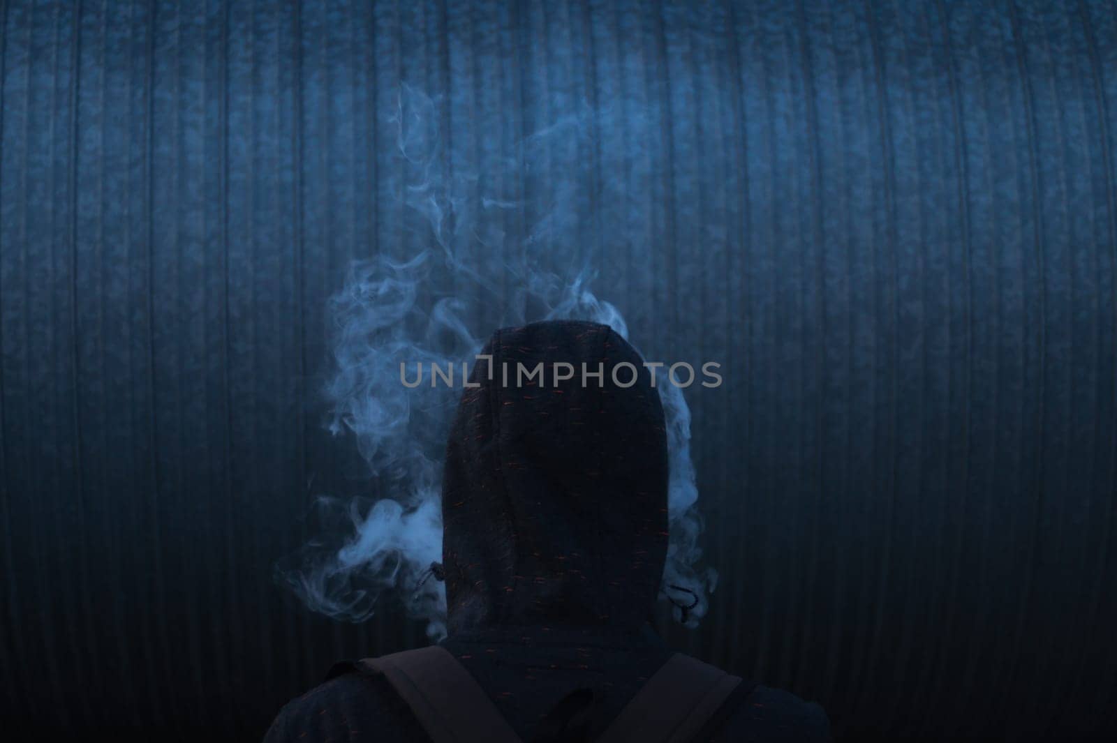 The man smoke an electronic cigarette on the dark background
