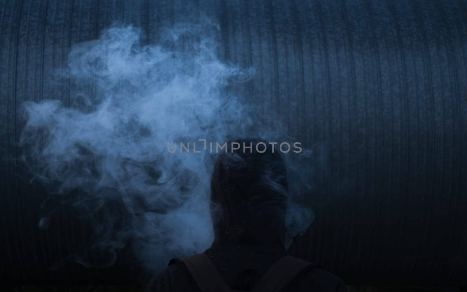 The man smoke an electronic cigarette on the dark background