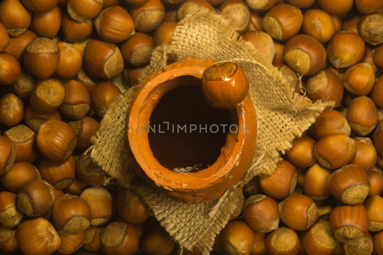 Honey pot with wooden spoon and nuts background