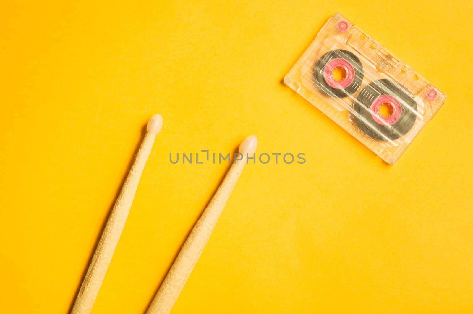 Drumsticks and audio cassette on yellow background