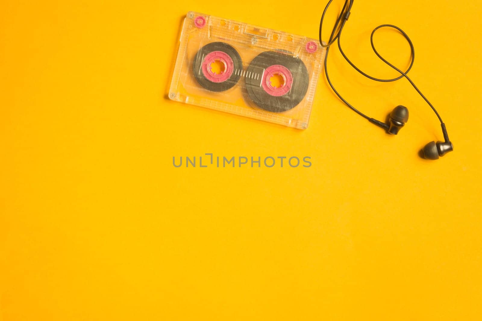 Earphones and retro cassette on yellow background. copy space
