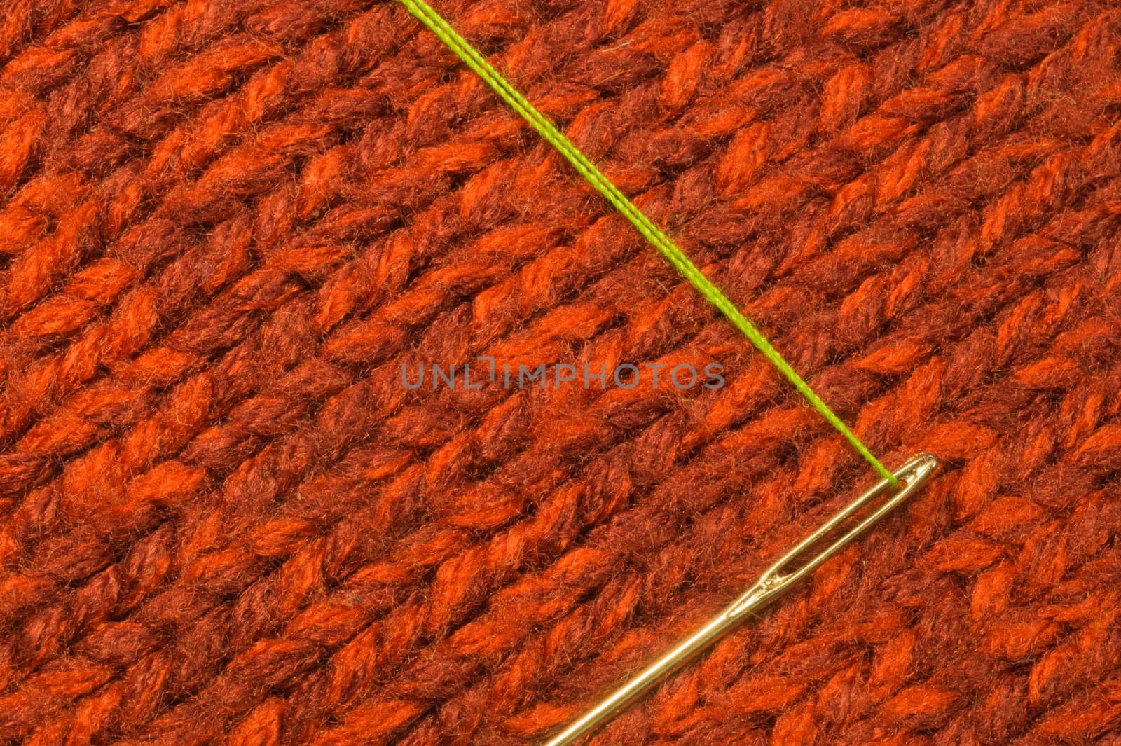 Needle with thread on red textile background. macro view