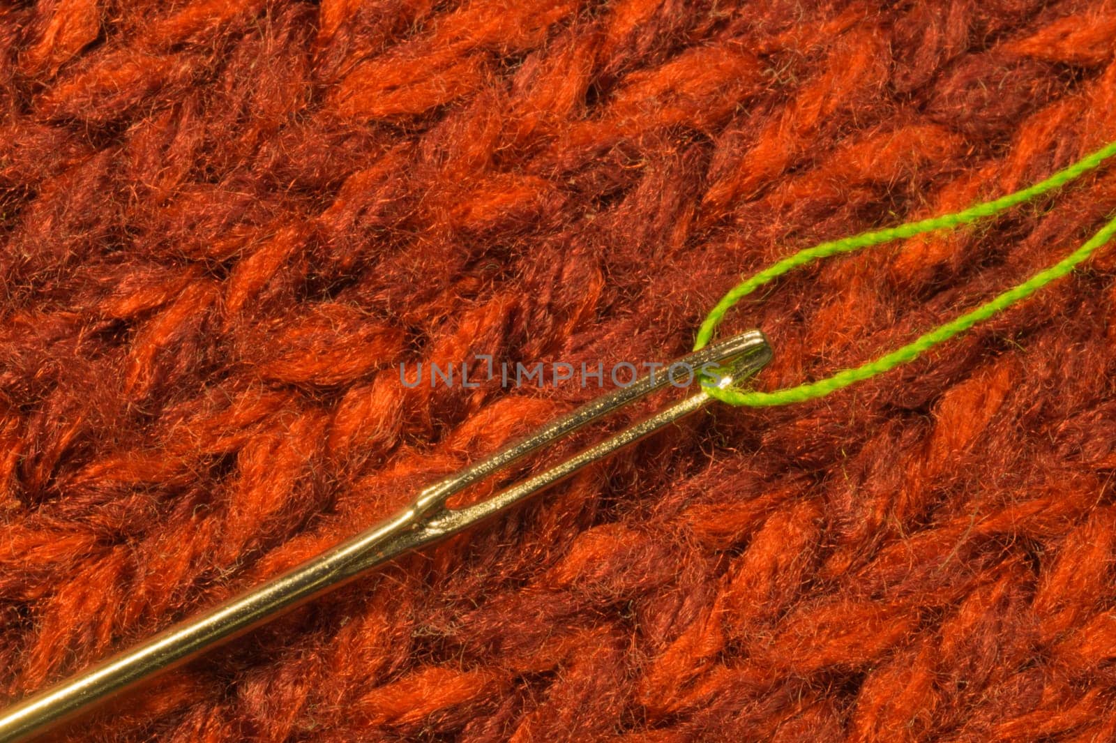 Needle with thread on red textile background. macro view