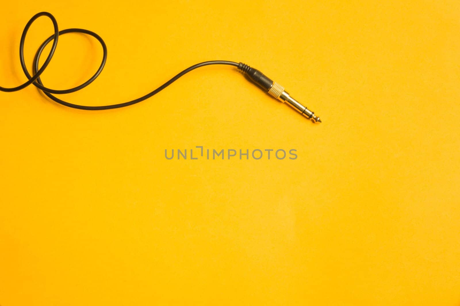 Audio jack with black cable isolated on yellow background