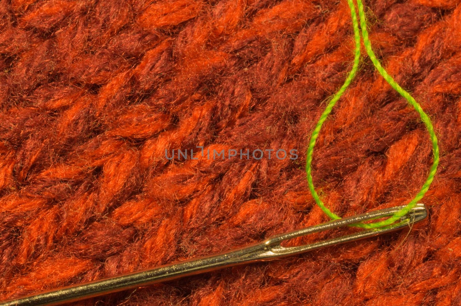 Needle with thread on red textile background. macro view