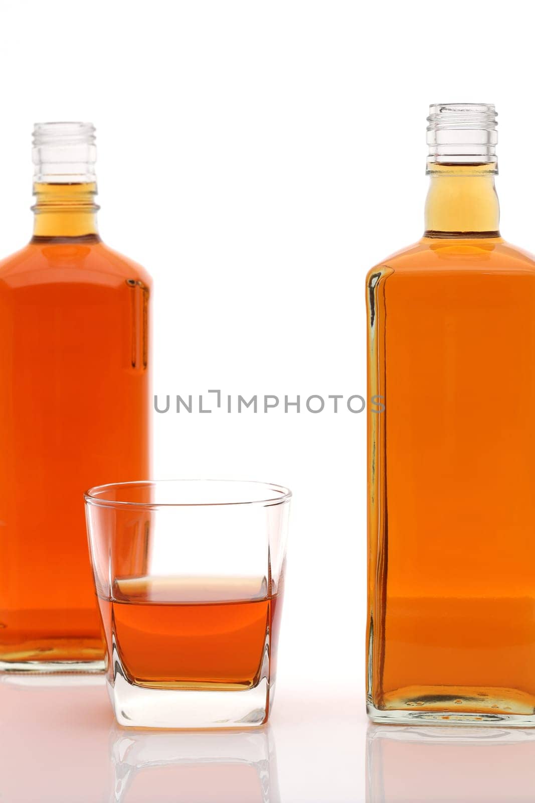 Glass cup and bottle of whiskey on white background