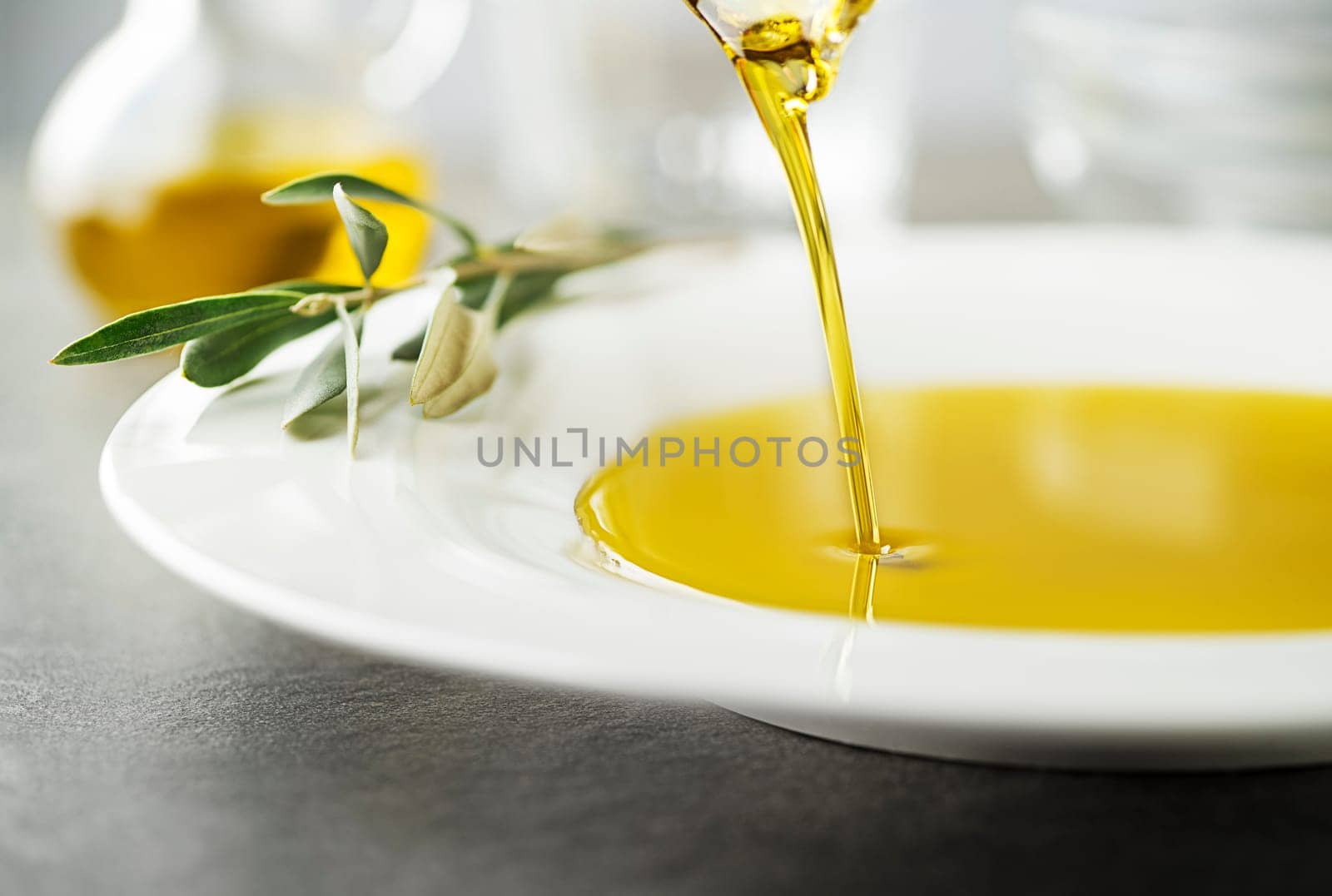 Bottle of healthy virgin olive oil pouring to plate close up. Healthy background concept