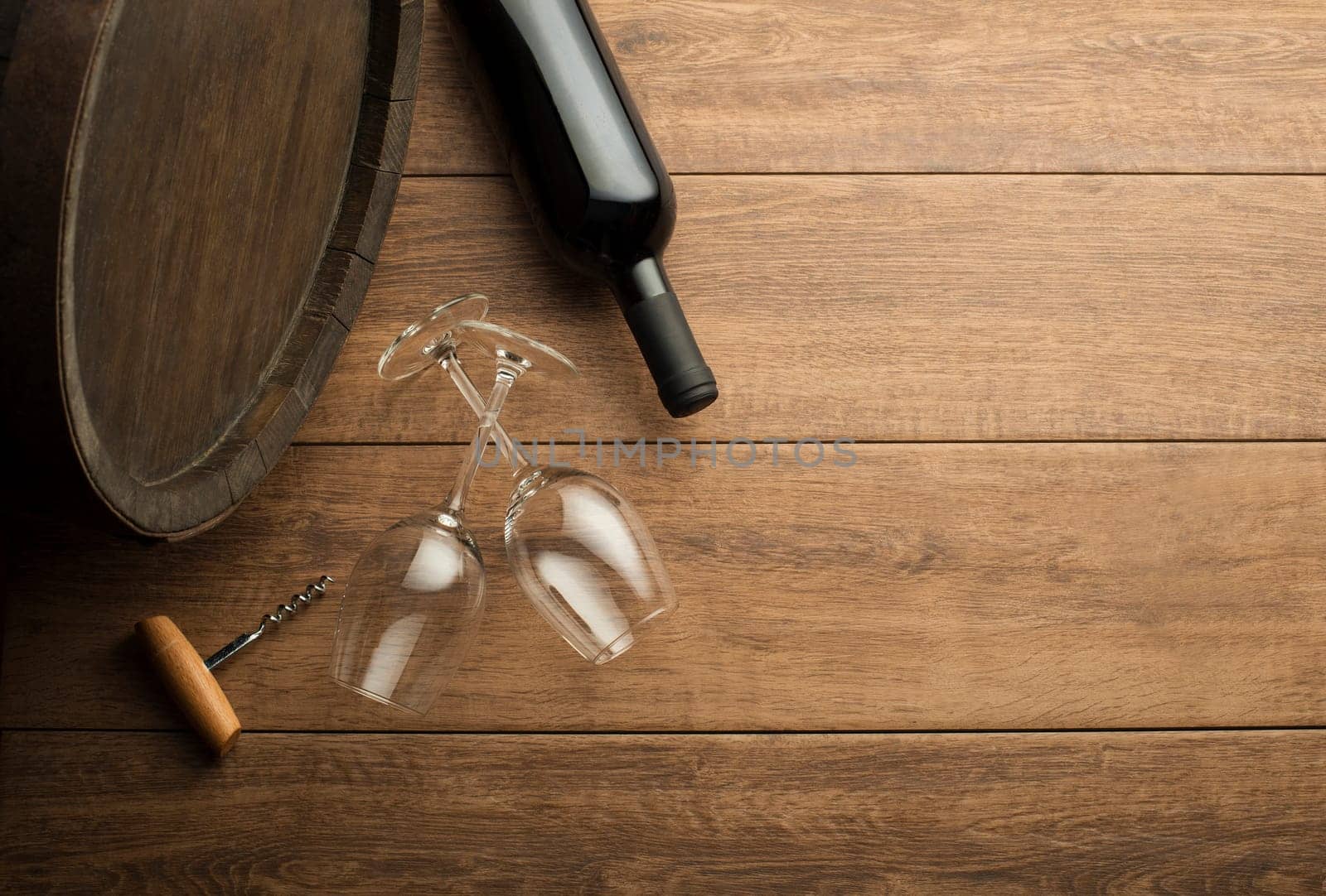 Bottle of red wine on old board. Wine bottle and glass with barrel background