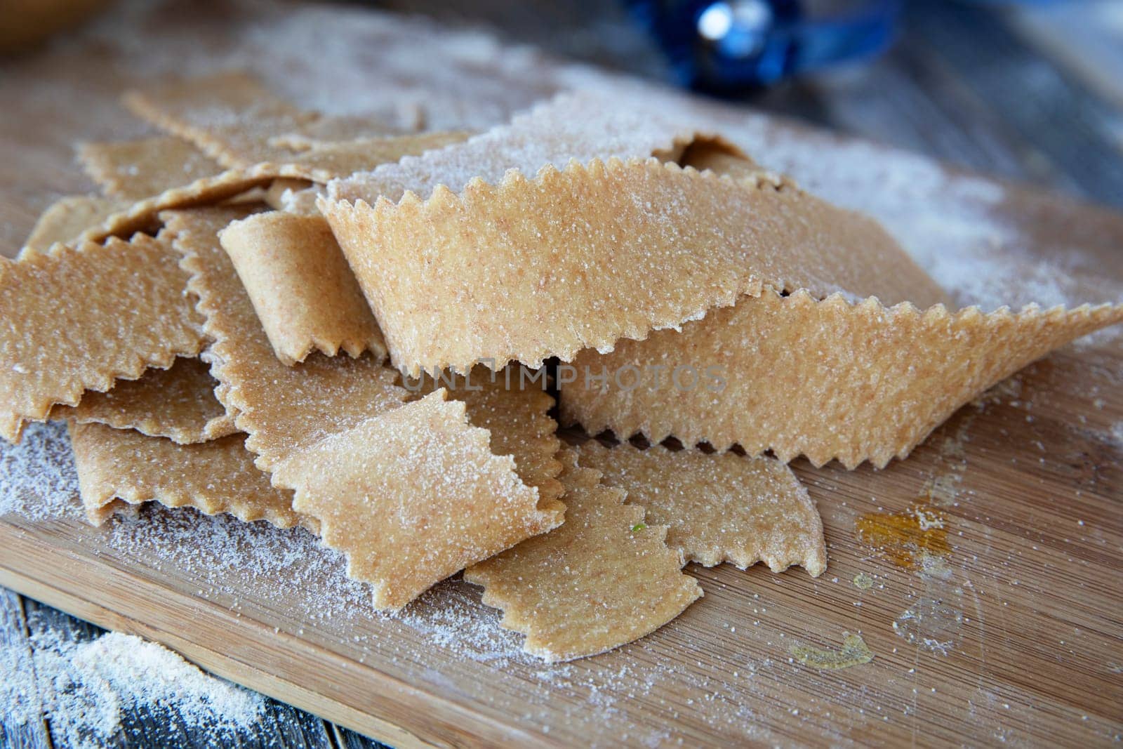 Fresh cut homemade pappardelle pasta on wooden board.