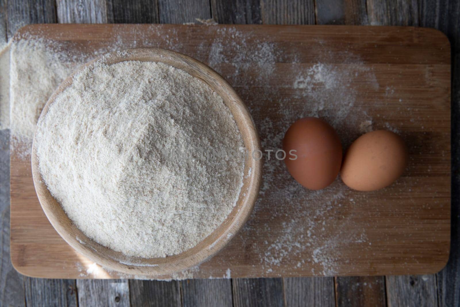 Bowl of whole wheat flour and two eggs on a cutting board.