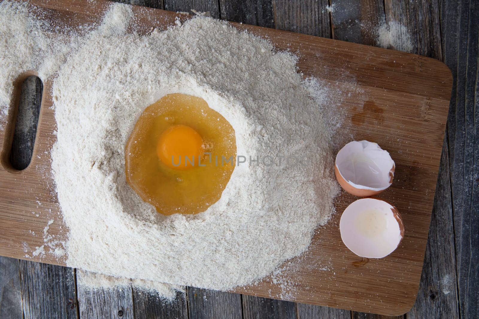 One eggs in flour well with egg shells on the side.