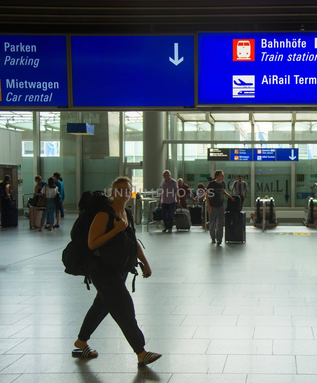 FRANKFURT AM MAIN, GERMANY - AUGUST 29, 2018: People with luggage exiting Frankfurt airport, Info board with direction signs above, Frankfurt am Main, Germany