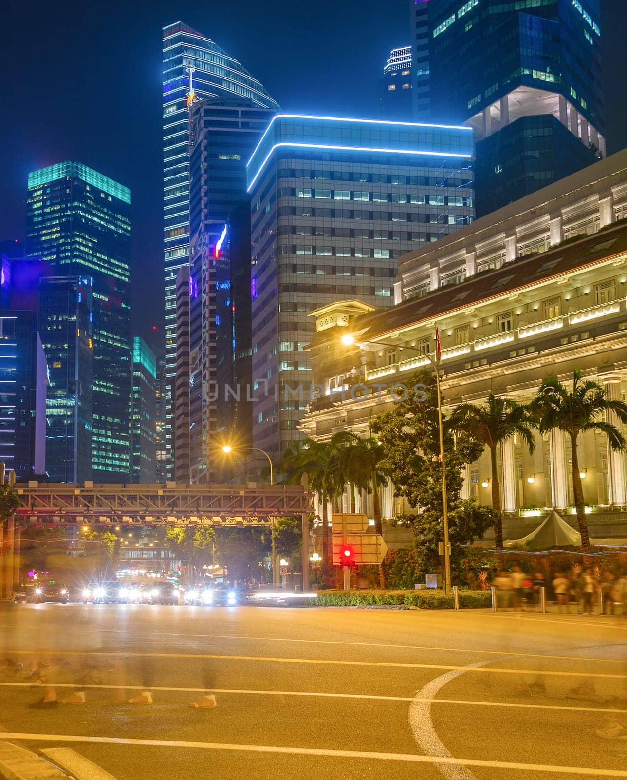 Singapore metropolis, Downtown core illuminated in night, crowd of people in motion blur crossing city highway, buildings of modern architecture in background