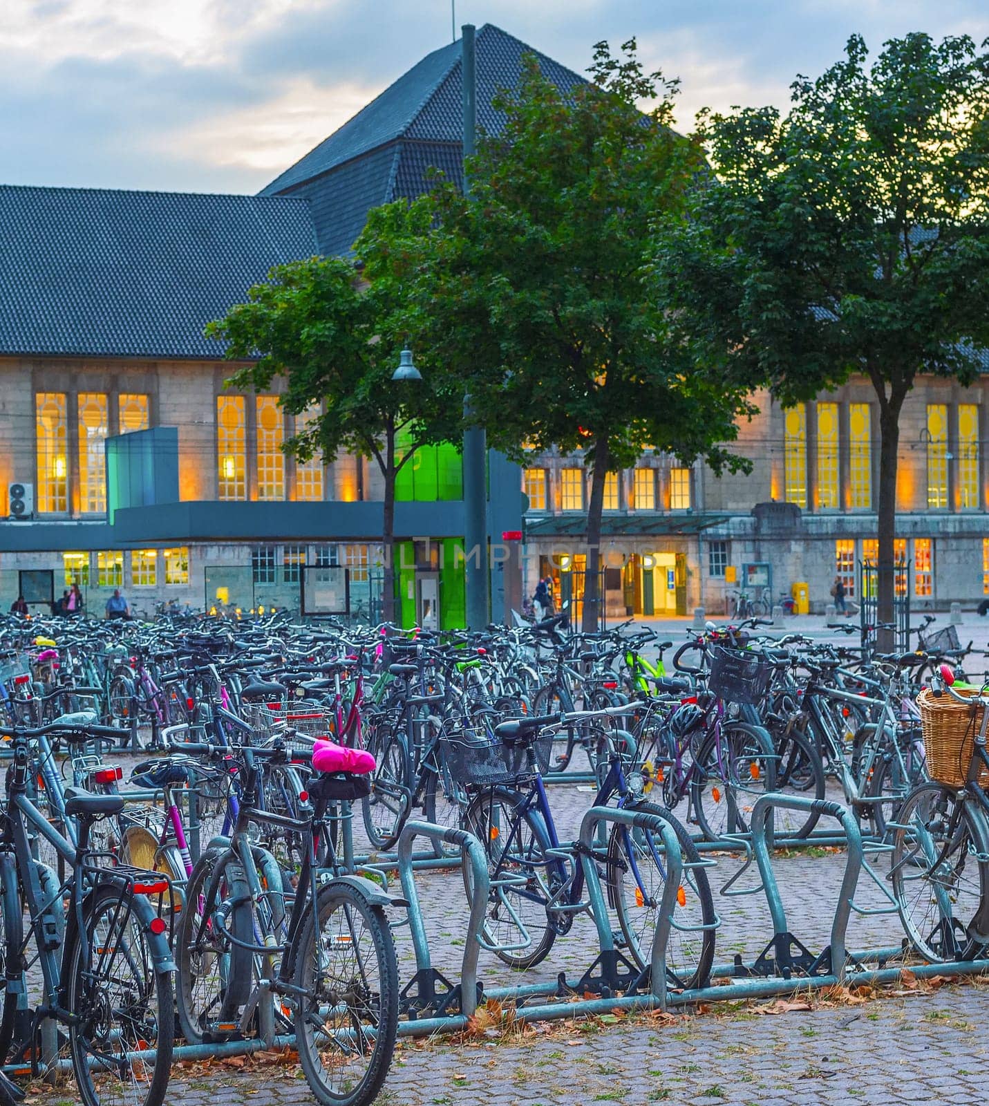 Big bicycles parking by train station in susnet dusk, Dortmund, Germany